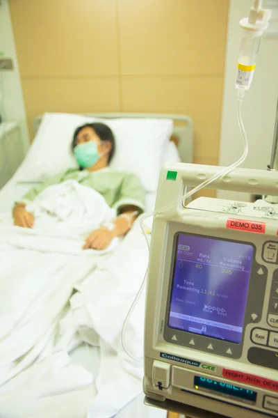 Pompa a goccia endovenosa IV in una stanza d'ospedale con paziente - Stock Fotografia Stock