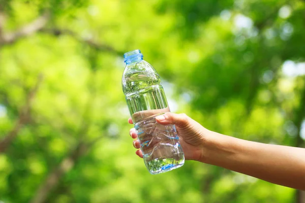 Archivbild - Frau hält Wasserflasche gegen grünen Rücken — Stockfoto