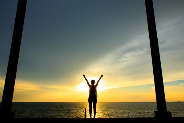 Foto d'archivio - donna a braccia aperte sotto il tramonto in mare — Foto Stock