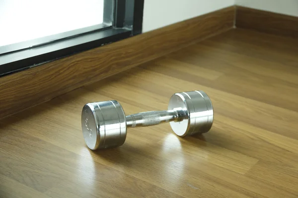 Steel dumbell on the wooden floor — Stock Photo, Image