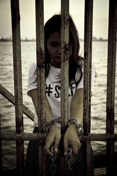 Stock Photo Stock Photo: Rusty chains, shackles binding the hands of a pretty young woman is tied to the iron and arrested. — Stock Photo, Image