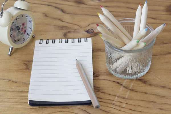 Stock Photo blank notebook on wooden table with alarm clock and pencils. Closeup — Stock Photo, Image