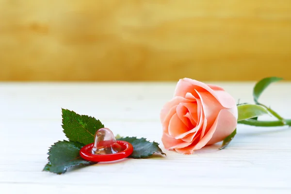 Zdjęcie z bliska z prezerwatywą i z bliska z różami na drewnianym stole — Zdjęcie stockowe