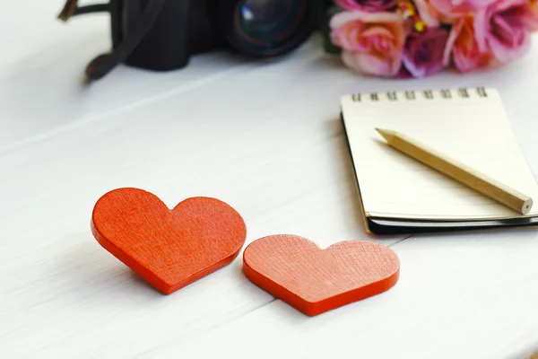 Stock Photo Corazón rojo de madera con cuaderno y cámara en tableros de madera blancos —  Fotos de Stock