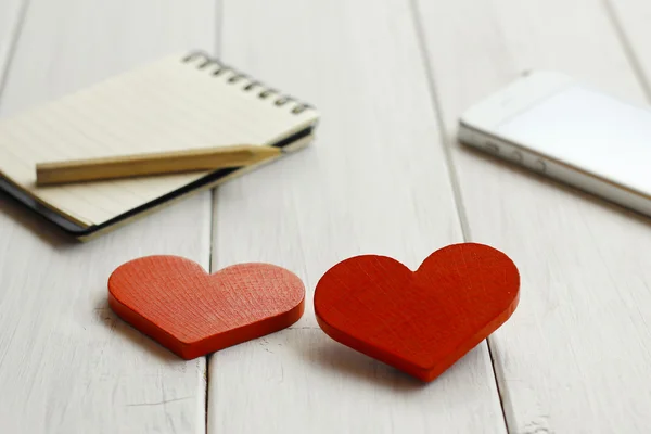 Stock Photo Corazón rojo de madera con cuaderno y cámara en tableros de madera blancos —  Fotos de Stock