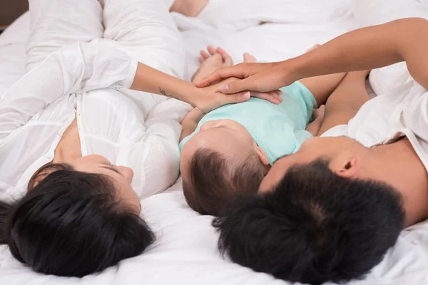 躺在床上抱着婴儿的父母 — 图库照片