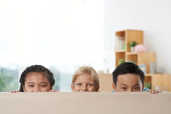 Дети прячутся за диваном — стоковое фото