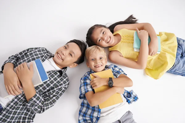 Enfants avec des manuels couchés sur le sol — Photo