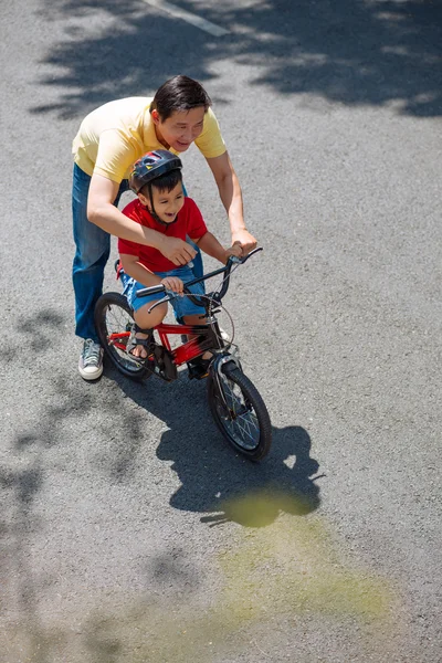 Homme aidant son fils à faire du vélo — Photo