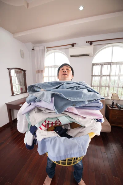 Homem carregando pilha de roupas sujas — Fotografia de Stock