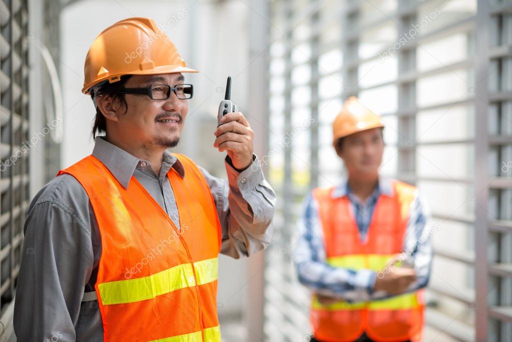 Asian foreman using walkie-talkie