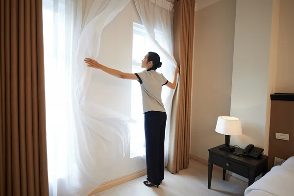 Hotel manager adjusting curtains — Stock Photo, Image