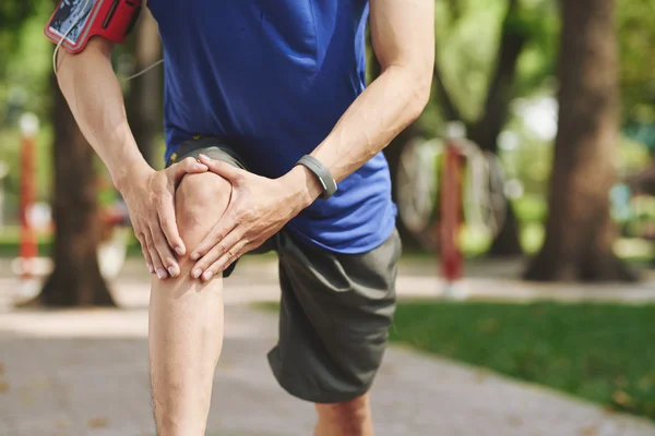 Mężczyzna otarcia kolana po joggingu — Zdjęcie stockowe