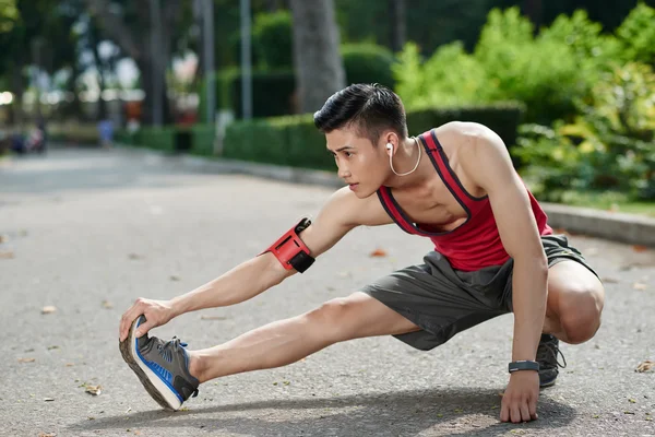 Giovane jogger stretching gambe — Foto Stock