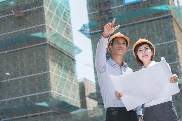 Engineers comparing blueprint with building — Stock Photo, Image