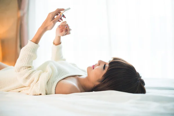 Mooie vrouw in bed texting — Stockfoto