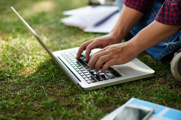 Man die typt op een laptop op gras — Stockfoto