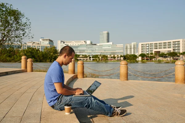 Mann an Böschung arbeitet am Laptop — Stockfoto