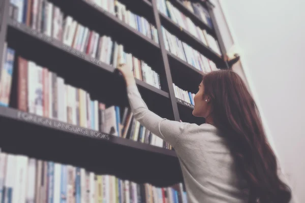 Mujer tomando libro de estante — Foto de Stock