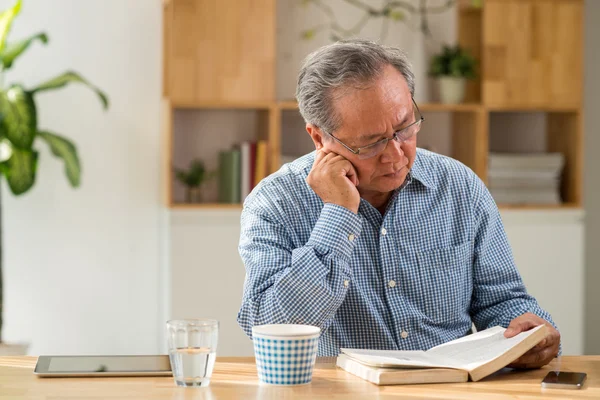 Mann am Tisch liest Buch — Stockfoto