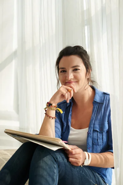 Vrouw met album zittend op de vloer — Stockfoto