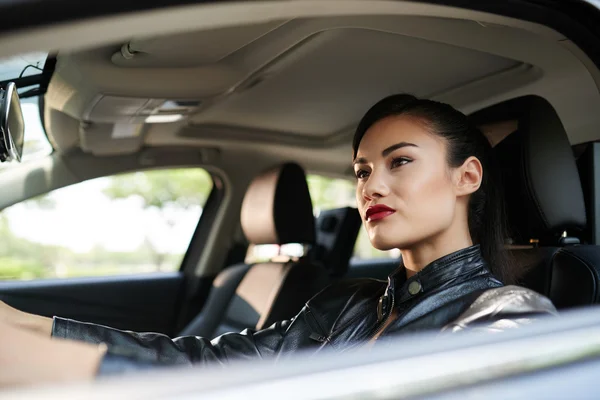 Mulher em couro casaco carro de condução — Fotografia de Stock