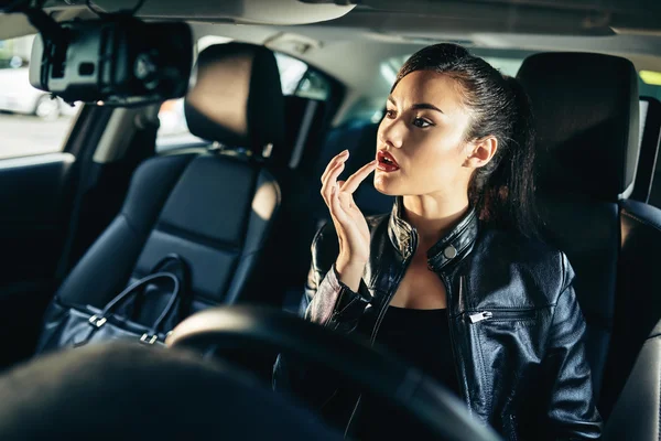 Mulher aplicando bálsamo labial no carro — Fotografia de Stock