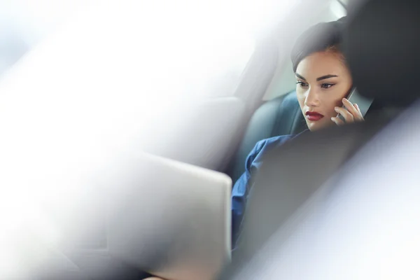 Woman talking on phone when sitting in taxi — Stock Photo, Image