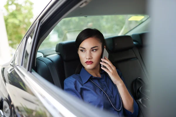 Woman sitting in car and talking on smartphone — Stock Photo, Image