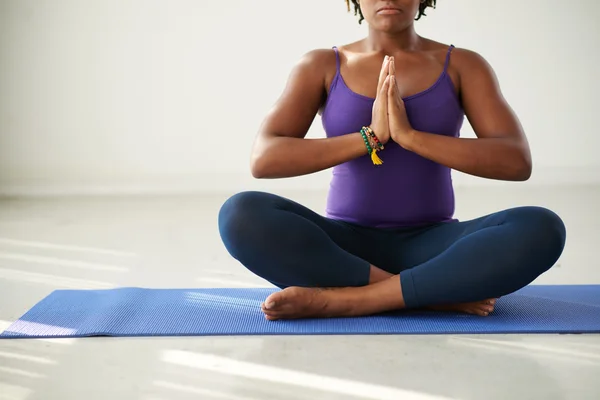 Mujer meditando sentada en una esterilla de yoga — Foto de Stock