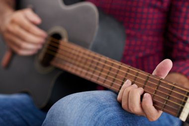 Adam akustik gitar çalıyor.