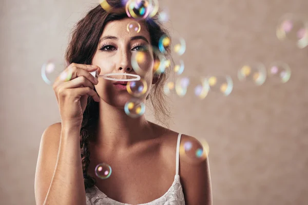 Brunette blowing soap bubbles — Stock Photo, Image