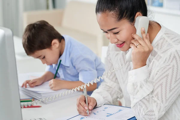 Mère occupée avec un petit fils au bureau — Photo