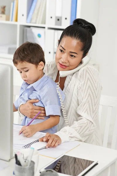 Femme d'affaires travaillant au bureau avec son fils — Photo