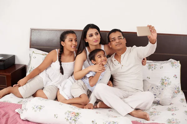 Famiglia prendendo selfie insieme a letto — Foto Stock