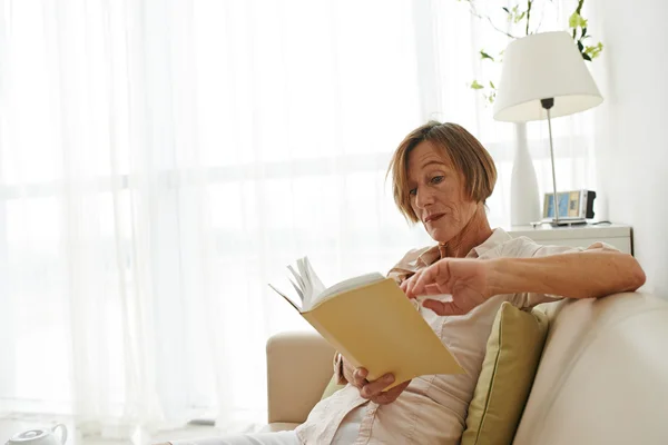 Aged woman reading a book at home — Stock Photo, Image