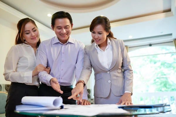 Par med mäklaren titta på house planerar — Stockfoto