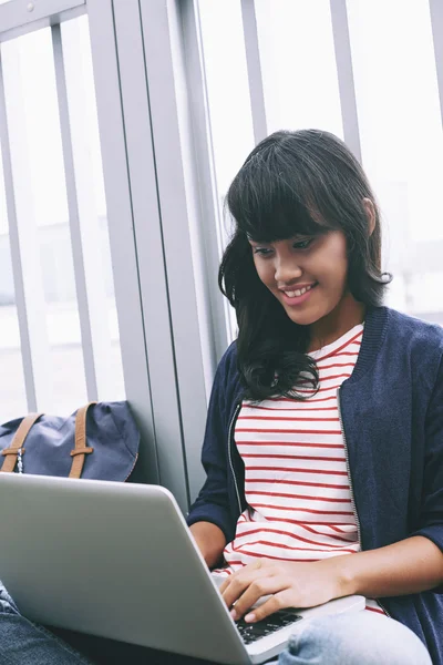 Frau tippt am Computer und lächelt — Stockfoto