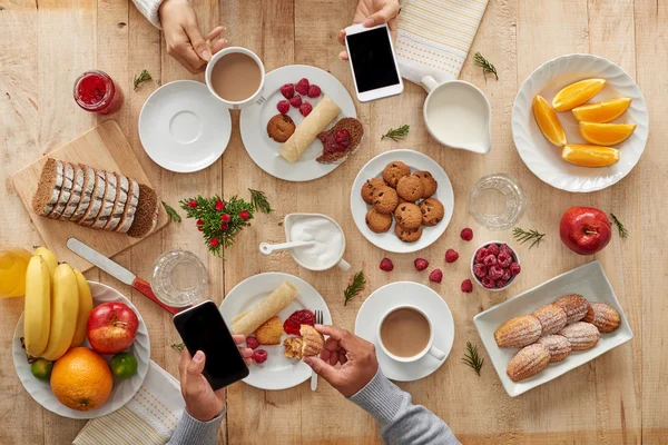 Casal tomando café da manhã com smartphones — Fotografia de Stock