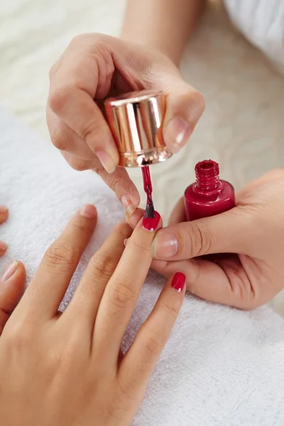 Master applying bright color to nails