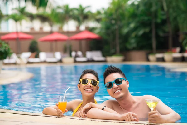 Casal com coquetéis refrescantes na piscina — Fotografia de Stock