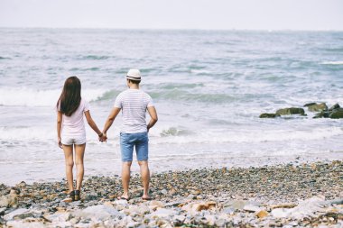 Çift el ele tutuşarak ve denizde seyir