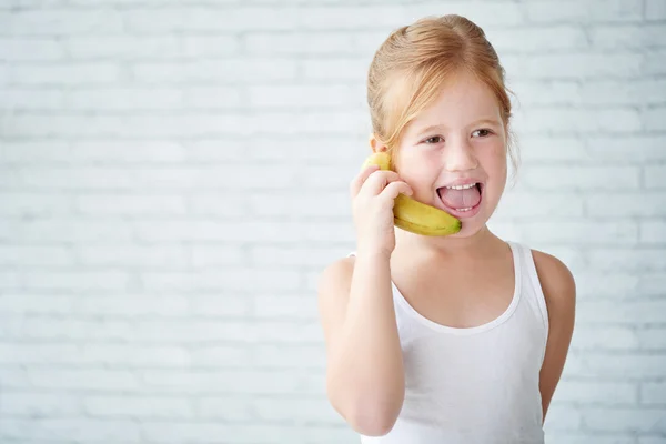 Jente som bruker banan istedenfor telefon – stockfoto