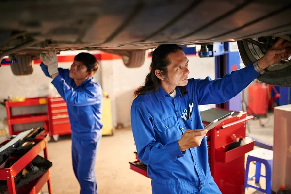 Mecánicos examinando el coche en el garaje —  Fotos de Stock