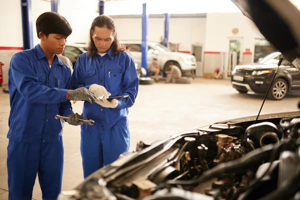Mekanik diskuterar bil defekter i garage — Stockfoto