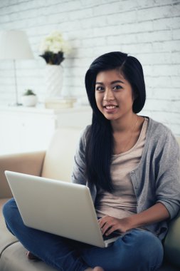 kanepede oturan ve dizüstü bilgisayarda çalışan kız