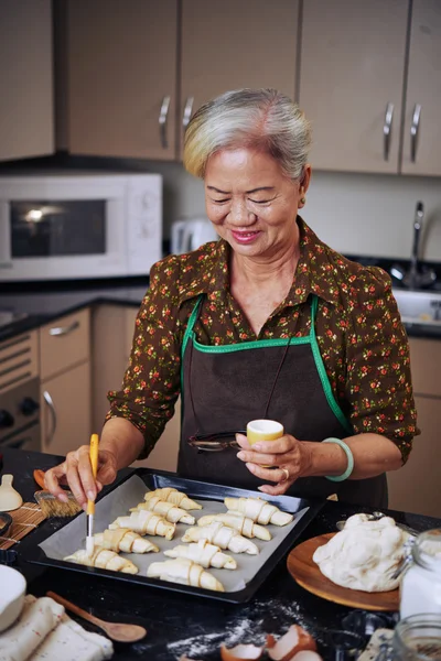 女人在早上做饭牛角面包 — 图库照片