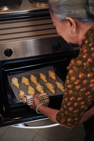 女人烤法国牛角面包 — 图库照片