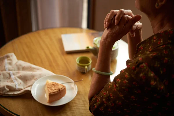 Kobieta z kawałkiem ciasta siedzi przy stole — Zdjęcie stockowe