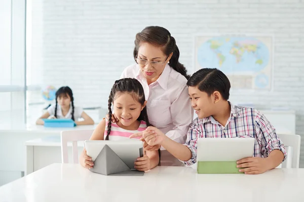 Leraar helpen kinderen met huiswerk — Stockfoto